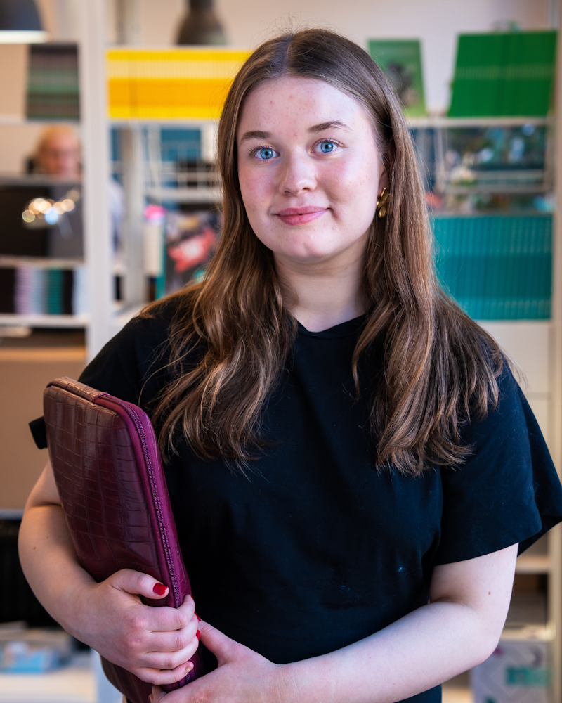 Cecilia håller i ett datorfodral och tittar in i kameran.